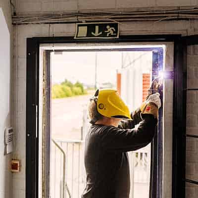 Man welding a door as part of DT Services maintenance plan